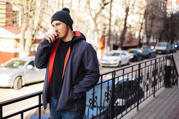 Young adult man outside and smoking tobacco device electronic cigarette heater. Smoke and steam...