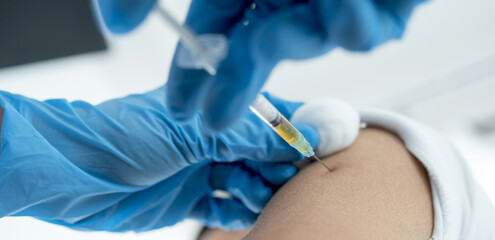 The doctor's hand holding a syringe and was about to vaccinate a patient in the clinic to prevent the spread of the virus
