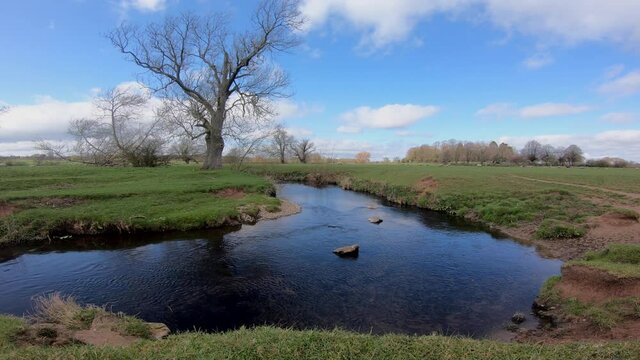 A sunny windy day on the river Arrow in Warwickshire, England as clouds roll over head.