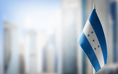 A small flag of Honduras on the background of a blurred background - obrazy, fototapety, plakaty