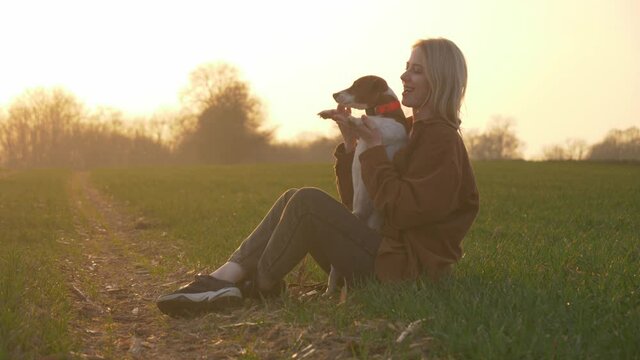 woman and dog are play the countryside road at sunset