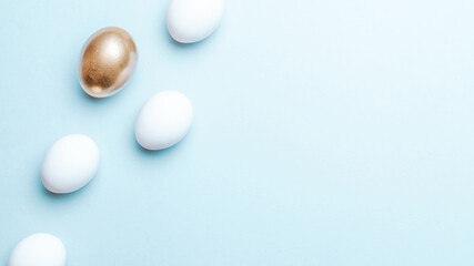 Easter luxury. Golden, white colour egg on pastel blue background in Happy Easter decoration. Flat lay, top view.