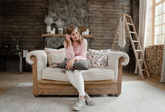 Girl At Home Sitting On The Couch And Holding A Pillow. Room In Vintage Style. Beautiful Girl Resting At Home. Portrait Of A Lovely Girl.