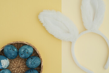 Creative Easter background with Easter eggs in the color of the night blue sky and bunny ears. Two-tone background in two shades of yellow. Space for text, flat lay, top view