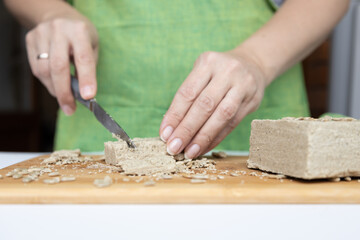 sunflower halva on a white table with seeds in women's hands