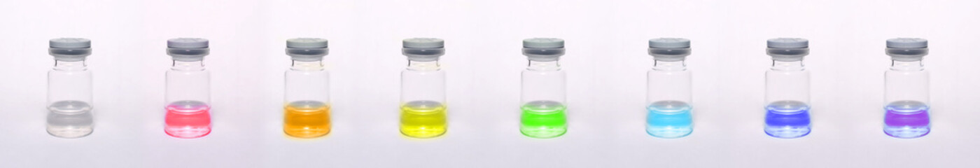 Medical bottles with rubber cover. Bottles half filled with rainbow colored liquid.