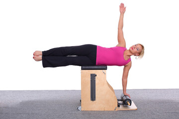 A 50-year-old trainer practices Pilates on an elevator chair by lying on her side and supporting...