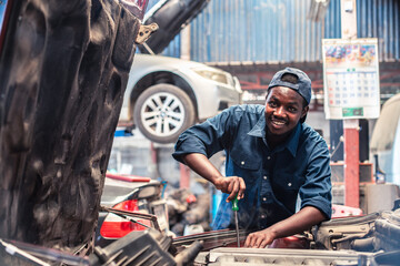 African maintenance male checking tire service via insurance system at garage with smile and happy