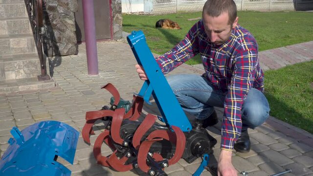 man assembles a cultivator for a tractor,the farm assembles a new cutter for the motoblock