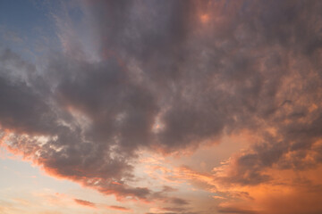 Naklejka na ściany i meble The sky at sunset before bad weather. Low red sunlight illuminates thunderclouds.