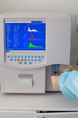 A medical laboratory assistant makes a blood test on an analyzer. Inserts a test tube into the apparatus.