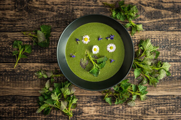 Healthy green spring nettle soup with edible flowers garnished with nettle leaves served on Green...