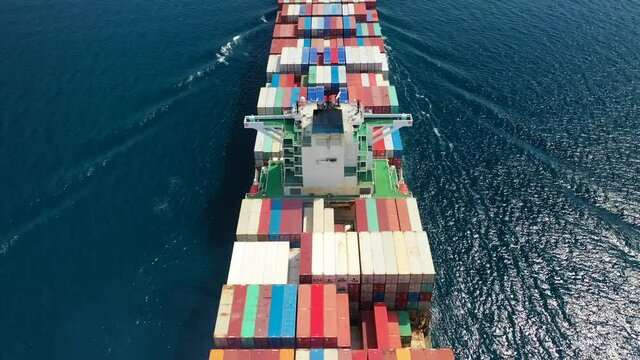 Aerial drone top view video of fully loaded container ship cruising open ocean sea for logistics import export, shipping or transportation