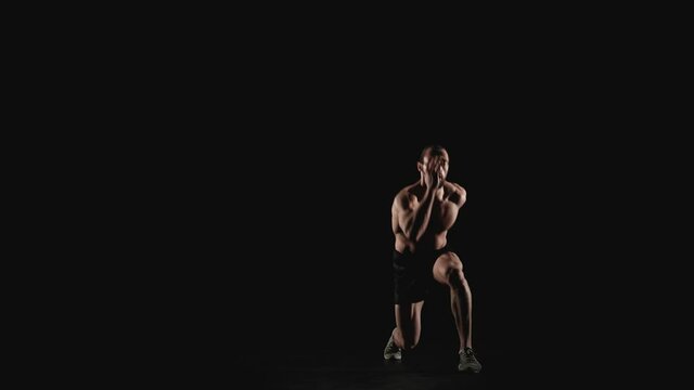 Sporty man doing physical exercises on a black background. Slow motion