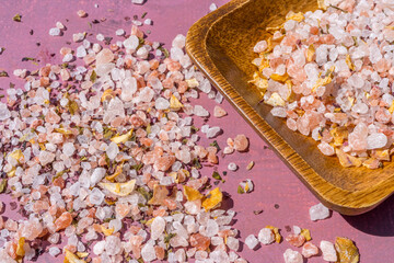 Macro close-up. Pink Himalayan crystal salt spice on a wooden spoon. Rose stone background.