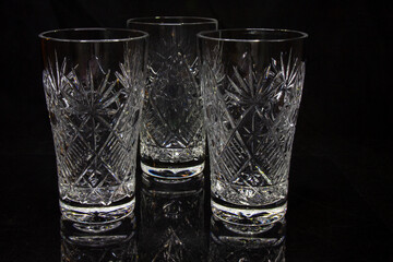 Three empty crystal bowls symmetrically on a black background with white and black beads