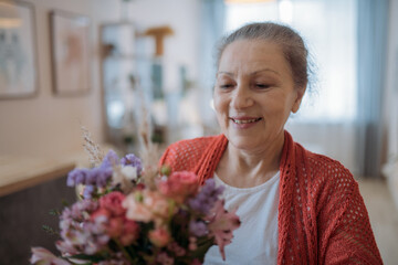 Portrait of an elderly woman holding flowers.