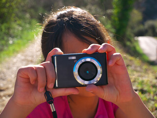 A mixed-race girl taking a photo with a red camera