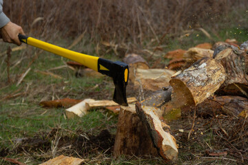 An ax with a yellow-black handle, chopping wood.