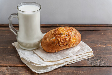 freshly baked diet bun and a mug of milk on a wooden table