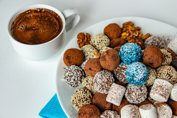 truffles with cocoa, coconut and sesame with chocolate and marshmallows and a cup of aromatic coffee, delicious dessert