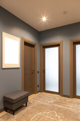Modern entrance hallway in neutral shades of brown and gray. tones. On the wall there is a photo frame with a mockup. The concept is fashionable interior design, the use of natural materials