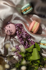 pink and mint french macaroons or macarons cookies and a lilac flowers on a cloth background. Natural fruit and berry flavors, creamy stuffing for valentines mother day easter with love food