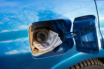 refill the car with fuel, some cash money inside the fuel tank, idea of expensive gasoline