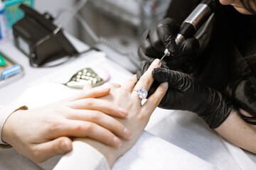process of hardware manicure in the salon, removing gel polish or acrylic from long nails with the...
