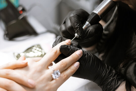 process of hardware manicure in the salon, removing gel polish or acrylic from long nails with the help of a manicure machine
