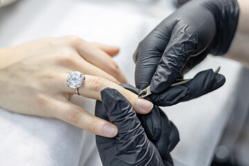 process of manicure in the salon on long nails, cutting the cuticle with a special tool