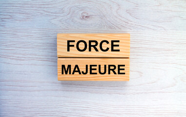 Wooden blocks with text Force Majeure on the wooden background