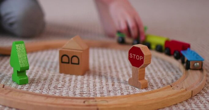 happy kid playing with wooden train on toy railway road at home