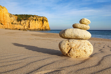 pile of pebbles on a sandy beach with cliff, balance, zen concept
