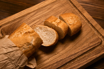 French bread baguette cut on vintage wooden bread board with knife.