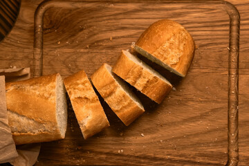 French bread baguette cut on vintage wooden bread board with knife.
