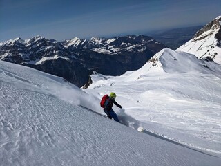 Fototapeta na wymiar Man skier rides through powder snow to the mountains. Winter sports freeride. Etscherzapfen in Glarus Swiss, Skimo