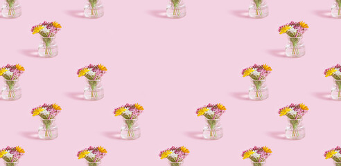 Creative pattern bouquet with mini bottle and wildflowers on pink background. Copy space. Banner format