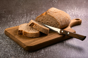 Fresh bread slice and cutting knife on cutting board
