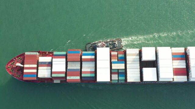 Aerial view of cargo ship carrying container for business import and export and tug
