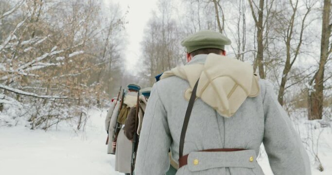 Men Dressed As White Guard Soldiers Of Imperial Russian Army In Russian Civil War Times Marching Through Snowy Winter Forest. Historical Reenactment