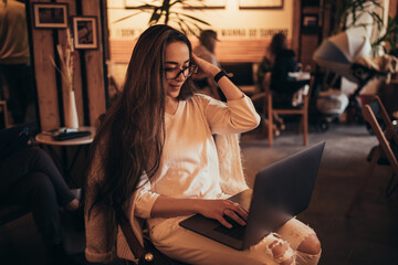 Young woman millennial sitting in a coffee shop and shopping online using her laptop and credit card.