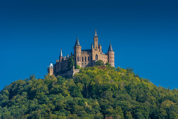 Fototapeta na wymiar Aerial view of famous Hohenzollern Castle, ancestral seat of the imperial House of Hohenzollern and one of Europe's most visited castles, on the top of a green hill in Baden-Wurttemberg, Germany