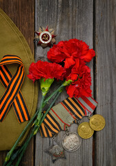 Victory Day.Order of the red star with the Russian inscription Patriotic war and medals on a wooden background with red carnations.Celebration on may 9.Memorial day.Greeting card.vertically