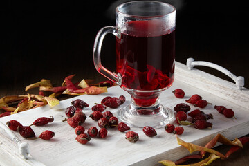 Hot winter drink surrounded by dried rose hips and apples