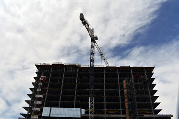 Low angle shot of a crane working on a construction of a building on a cloudy day