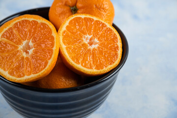 Close up photo of black bowl full with whole or half cut mandarins