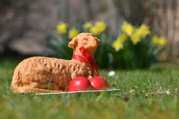 Ostereier und ein gebackenes Osterlamm in einer Wiese mit gelben Blumen im Hintergrund - Easter...