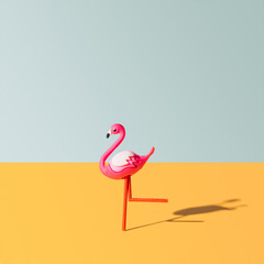 One pink flamingo toy looks like runing. Bright optimistic orange and light gray background.