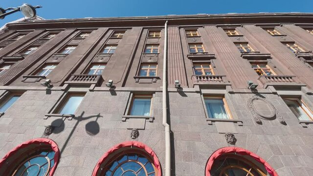 Facade of the beautiful ancient building in a clear sunny weather, the bottom view, sun-protection peaks of red color, big windows, the blue sky, effect of a wide lens, Russia, St.Petersburg